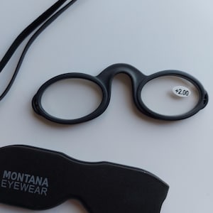Op de afbeelding: Zwarte leesbril met een +2,00 vergroting, een zwart koord en een zwarte etui met de tekst "MONTANA EYEWEAR".