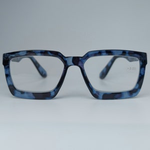 May include: Blue and black tortoise shell eyeglasses with clear lenses. The right lens has the text +3.00 printed on it.