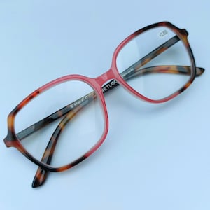 May include: A pair of pink and tortoise shell reading glasses with a +2.50 lens strength. The glasses have a square frame and are made of plastic.