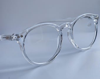 May include: Clear, transparent round-frame glasses with a glossy finish. The frames feature a keyhole bridge and silver-toned metal rivets at the hinges. The right lens is clearly marked with the text +2.50 in a small, black font.