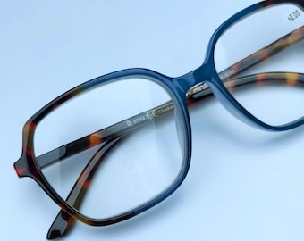 Könnte beinhalten: Rechteckige Brille mit dunkelblauem Rahmen und Schildpatt-Bügeln. Die Gläser sind klar, und das rechte Glas hat eine +2,00-Markierung. Der Rahmen ist mit "EP 62" und "53-17-M" gekennzeichnet.