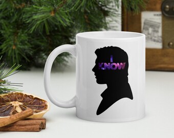 Może przedstawiać: Biały kubek ceramiczny z czarną sylwetką głowy Hana Solo. Tekst "I KNOW" jest napisany na jego oczach w fioletowym i różowym wzorze galaktyki.