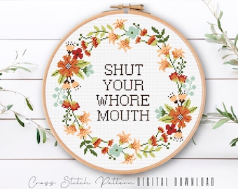 Könnte beinhalten: Ein Kreuzstichmuster mit einem Blumenkranz, der den Text "SHUT YOUR WHORE MOUTH" umgibt.