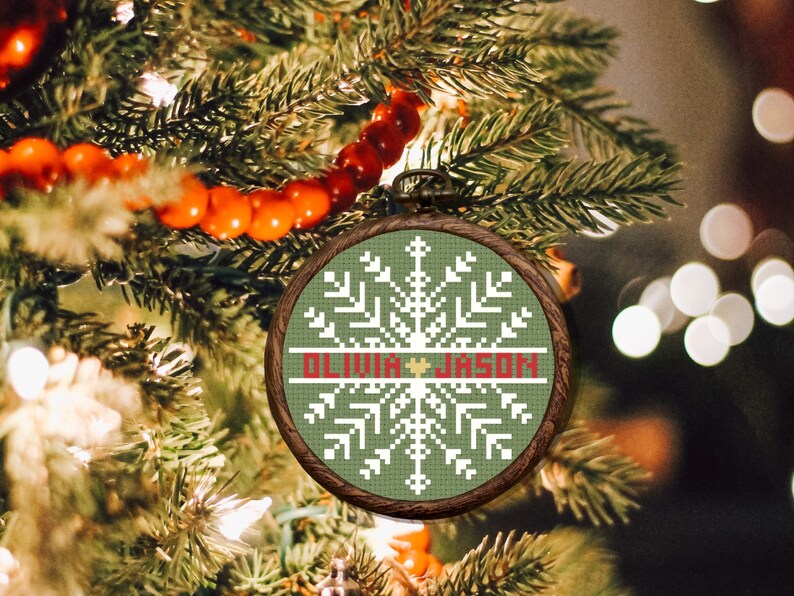May include: A green and white cross-stitch ornament with a snowflake design and the names "Olivia" and "Jason" in red.