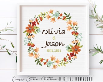 Può includere: Schema di punto croce con una ghirlanda di fiori con i nomi Olivia & Jason e la data 10.12.2022.