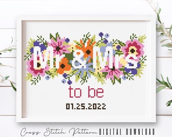 May include: Cross stitch pattern with the words "Mr. & Mrs. to be" surrounded by colorful flowers. The date "01.25.2022" is below the text.