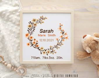 May include: A cross stitch pattern featuring a floral wreath with the name "Sarah Marie Smith" and the date "12.10.2021". The pattern also includes the time "7:13am", weight "7 lbs. 5oz", and length "20in".