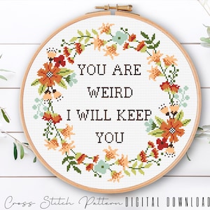 Może przedstawiać: Wzór do haftu krzyżykowego z wieńcem kwiatowym i tekstem "You are weird I will keep you".