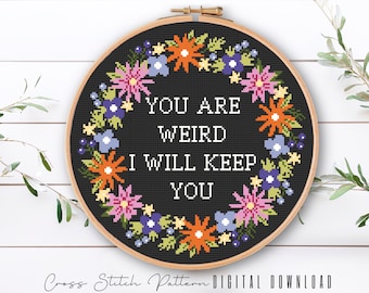 May include: A black and white cross stitch pattern with a floral wreath surrounding the text "You are weird I will keep you".