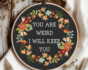 May include: A black embroidery hoop with a floral wreath design and the text "You are weird I will keep you".