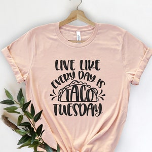 May include: A peach-coloured t-shirt with the text "Live like every day is Taco Tuesday" in black lettering. The text includes a graphic of a taco.
