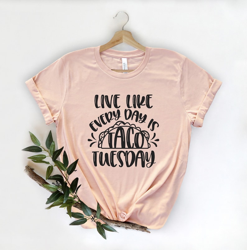May include: A peach-coloured t-shirt with the text "Live like every day is Taco Tuesday" in black lettering. The text includes a graphic of a taco.