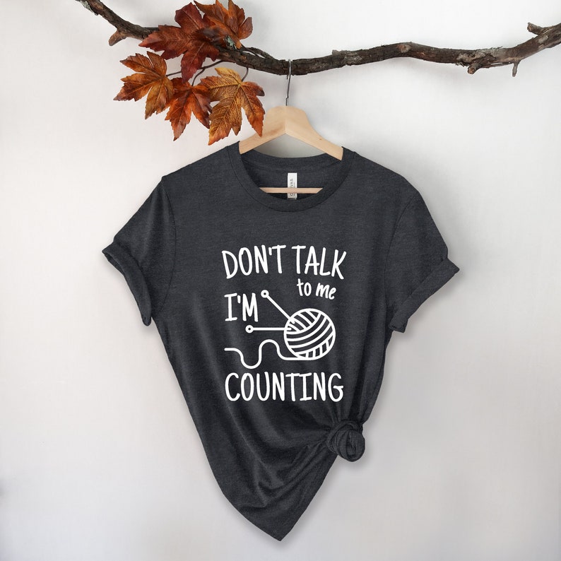 May include: A dark gray t-shirt with the text "Don't talk to me I'm counting" and a graphic of a ball of yarn and knitting needles.