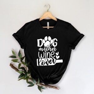 May include: Black t-shirt with white text that reads "Dog mother wine lover" with a paw print and wine bottle graphic.