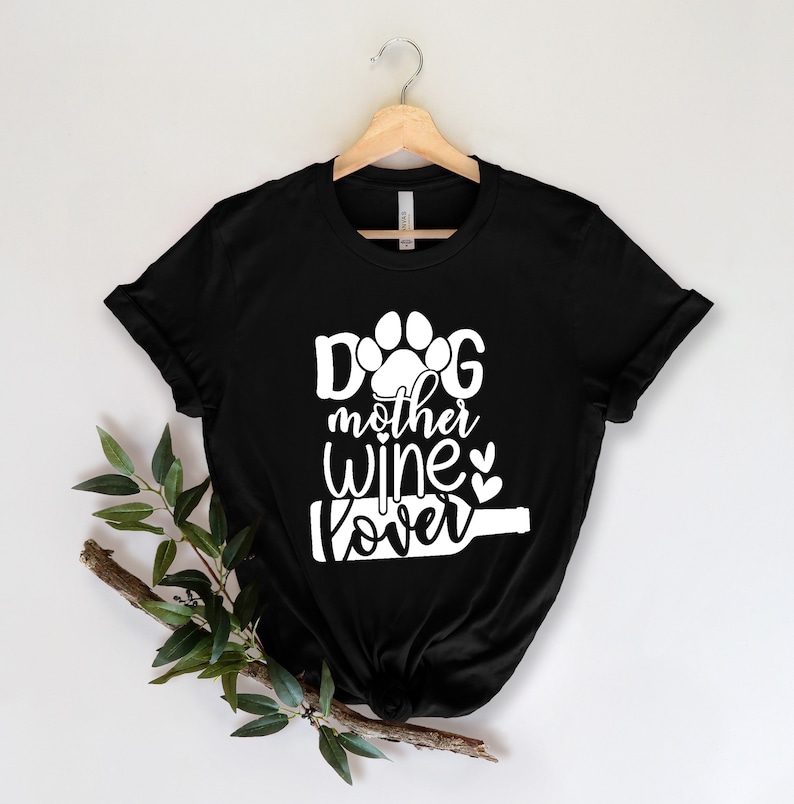 May include: Black t-shirt with white text that reads "Dog mother wine lover" with a paw print and wine bottle graphic.