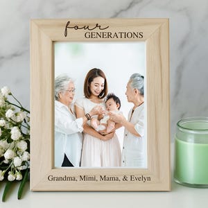 May include: A light-colored wooden picture frame with the words "four generations" engraved at the top. The frame holds a family photo of four generations. A yellow rose and a green candle are next to the frame.