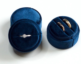 May include: Two blue velvet ring boxes. One box contains a single ring with a small diamond, the other box contains two rings.