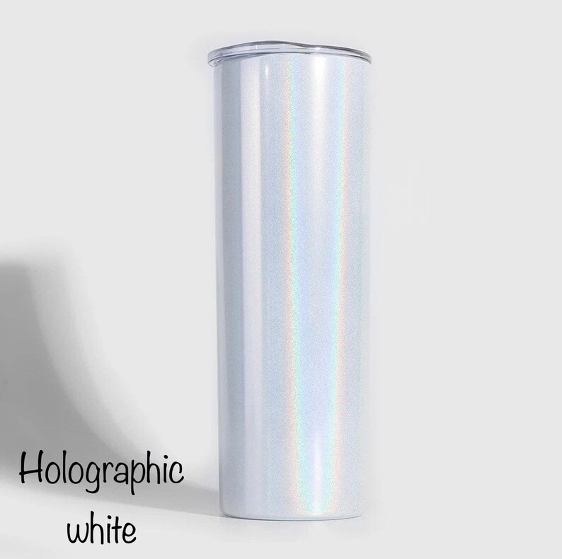 May include: A white tumbler with a holographic finish. The tumbler has a clear lid and is made of stainless steel.