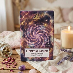 May include: A box of oracle cards with the title "Liebeskummer" and the text "Orakelkarten Manoja Esoterik". The box has a purple and gold cosmic design with a spiral in the center. The image also includes amethyst and rose quartz crystals.
