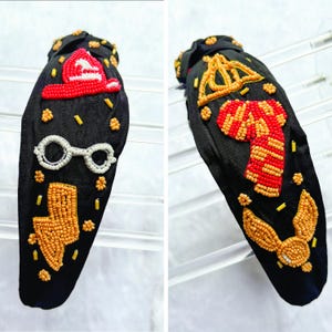 May include: Black headband with beaded designs. One side features a red firefighter's hat, white glasses, and a gold lightning bolt. The other side has a gold crown, a red and gold scarf, and a gold winged emblem.