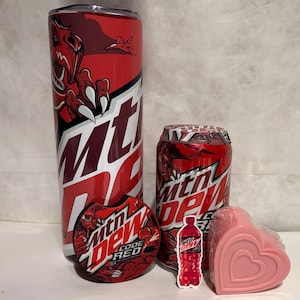 May include: A set of Mountain Dew Code Red themed items including a red and white tumbler, a can of soda, a round coaster, a sticker of a can of soda, and a pink heart-shaped soap.