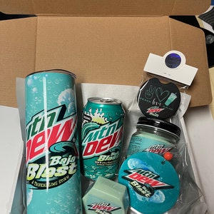 May include: A gift box filled with Mountain Dew Baja Blast themed items, including a tumbler, can, soap, car air freshener, and a round car air freshener with the text "Peace Love Baja Blast".