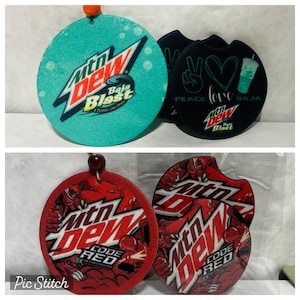 May include: Four round, colorful, fabric coasters featuring the Mountain Dew logo. Two coasters are green with the text "Baja Blast" and two coasters are red with the text "Code Red".