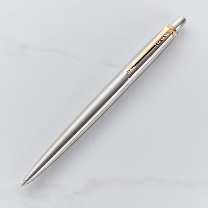 May include: A silver ballpoint pen with a gold-colored top and clip.