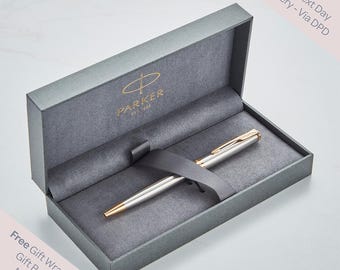 May include: A silver and gold Parker pen presented in a gray gift box. The pen is secured with a gray ribbon. The box has the Parker logo in gold. Text on the box reads "Free Gift Wrapping, Gift Bag and Message".