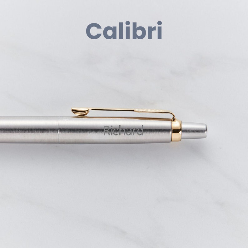 May include: A silver pen with a gold clip and a gold band at the end. The pen is engraved with the name "Richard".