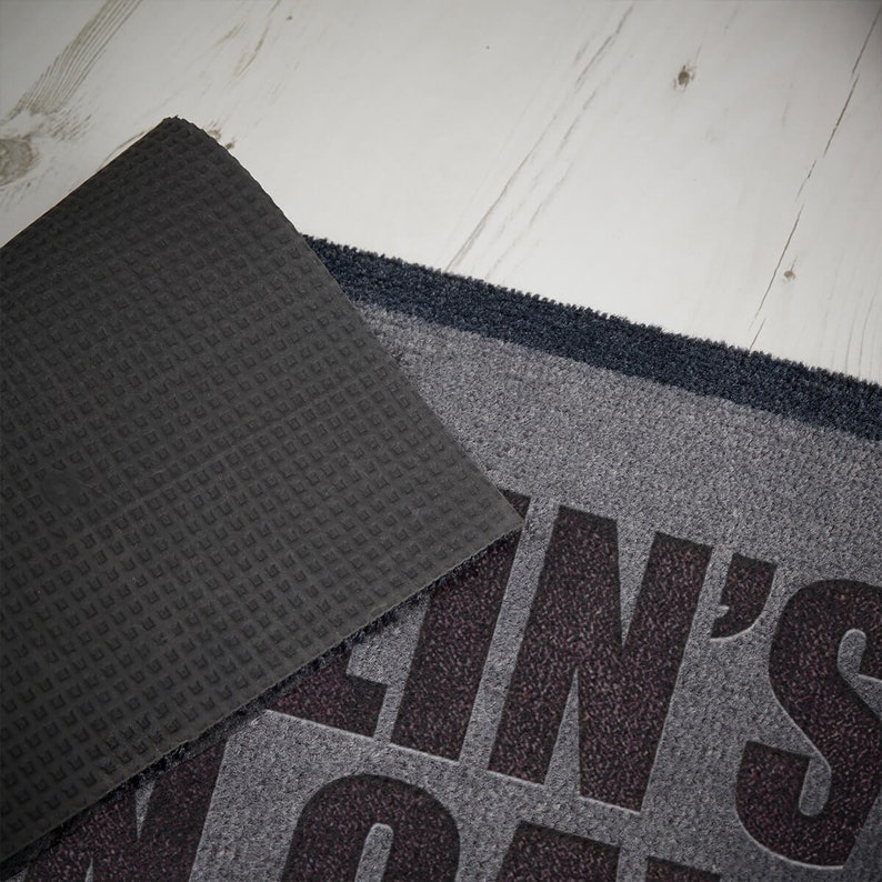 May include: A gray doormat with the text "Clean's Not My Gift" in black. The doormat has a black rubber backing.