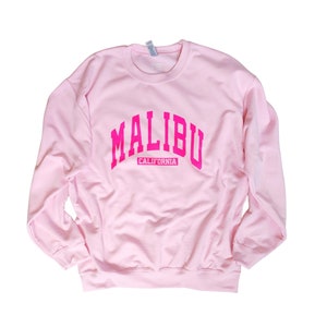 Op de afbeelding: Roze sweatshirt met een roze "MALIBU CALIFORNIA" afbeelding.