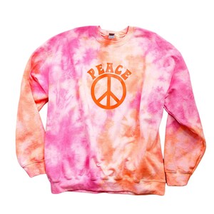 May include: A pink and orange tie-dye sweatshirt with a large orange peace sign and the word "PEACE" in orange letters above it.