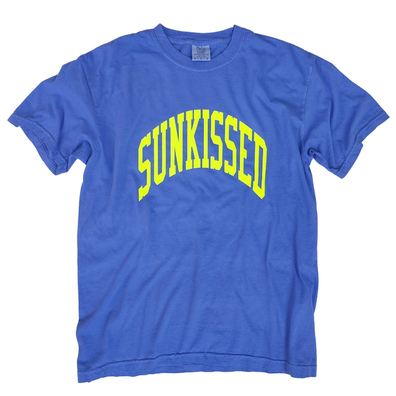 May include: A blue t-shirt with a yellow "SUNKISSED" graphic printed on the front.