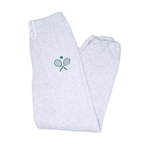 May include: Gray sweatpants with a green tennis racket and ball design.