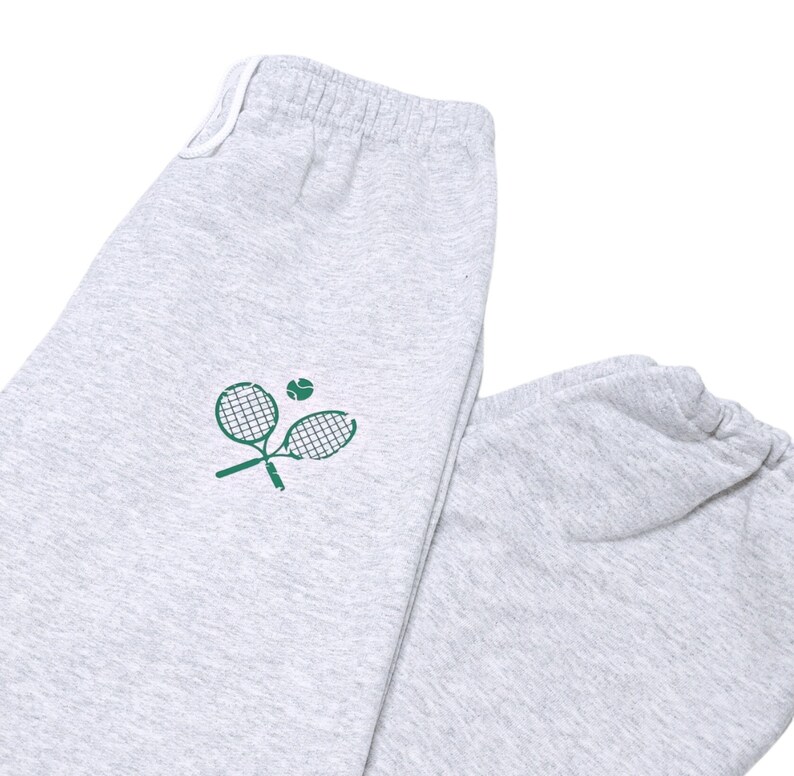 May include: Gray sweatpants with a green tennis racket and ball graphic.