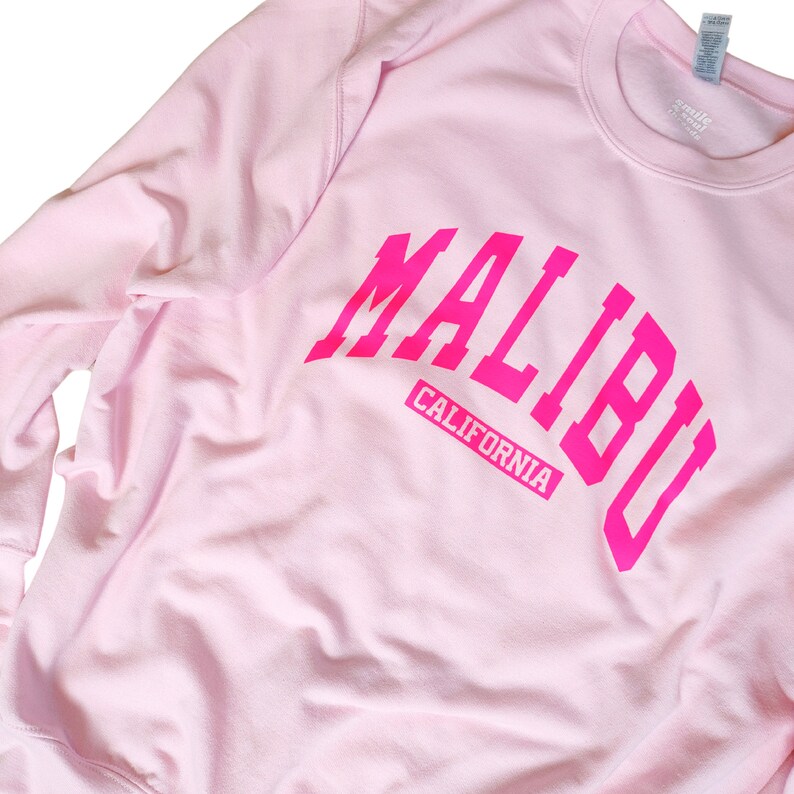 Op de afbeelding: Roze sweatshirt met een roze "MALIBU CALIFORNIA" afbeelding.
