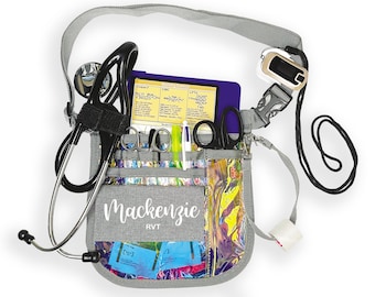 May include: A gray medical bag with a rainbow iridescent pattern. The bag has a variety of pockets and compartments for medical supplies. It includes a stethoscope, scissors, a pen, a pulse oximeter, and a notepad. The bag has a personalized name tag that reads "Mackenzie RVT".