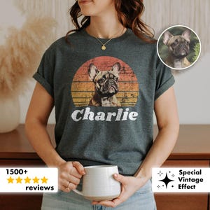 May include: Dark gray t-shirt featuring a French Bulldog graphic within a sunset-style circle. The dog's name, "Charlie," is printed in white below the image. The shirt has short sleeves.