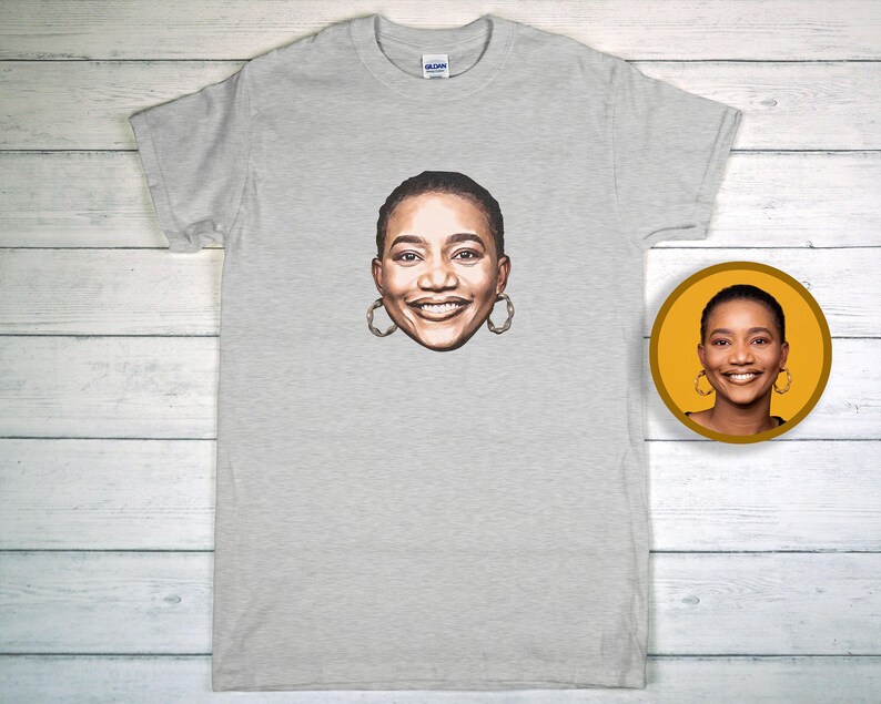 May include: A pale grey t-shirt with a portrait of a smiling person wearing hoop earrings. A smaller, circular image of the same portrait is on the right. The shirt is made of a soft material.