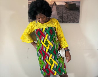 May include: A yellow and green patterned dress with a yellow lace overlay and bell sleeves. The dress is knee-length and has a fitted bodice.
