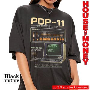 May include: Black oversized t-shirt featuring a vintage computer graphic with the text "PDP-11" and "Born to Run". The design includes retro computer components and text. The shirt is labeled "House of Money".