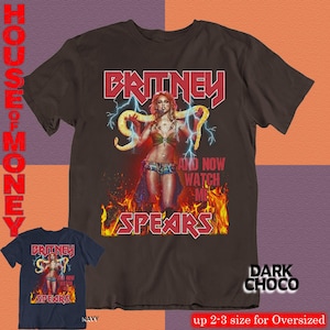 May include: Dark chocolate brown t-shirt featuring a graphic of Britney Spears with the text "BRITNEY SPEARS" in red. The design includes lightning bolts and flames. A navy blue t-shirt with the same design is also shown.
