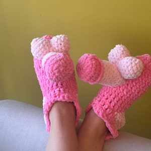 Peut inclure: Chaussons en crochet rose et blanc avec une texture moelleuse. Les chaussons ont un design unique avec une forme arrondie en haut.