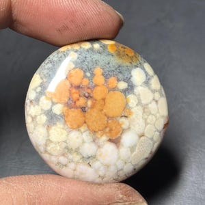 Puede incluir: Una taza de cerámica blanca con asa negra y el texto "But First, Coffee" en negrita negra. La taza se encuentra sobre un fondo borroso, sugiriendo un ambiente acogedor. La taza mide aproximadamente 10 cm de altura.