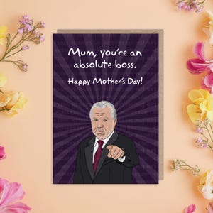 May include: A greeting card with a purple background and a cartoon image of a man in a suit. The text on the card reads "Mum, you're an absolute boss. Happy Mother's Day!"