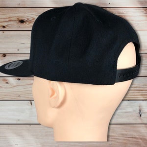 May include: A black, flat-brimmed baseball cap with a black adjustable strap in the back.