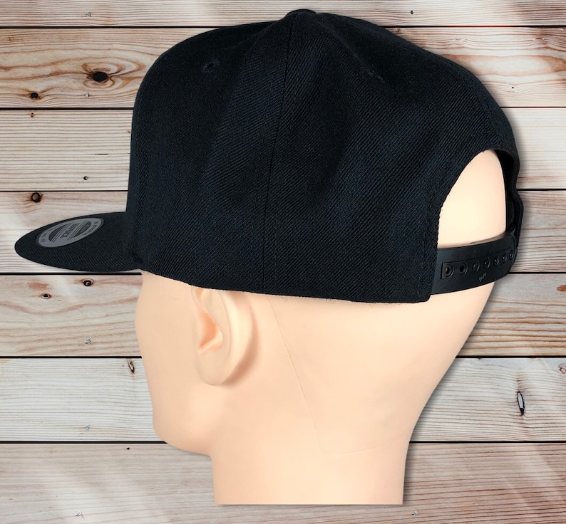 May include: A black, flat-brimmed baseball cap with a black adjustable strap in the back.