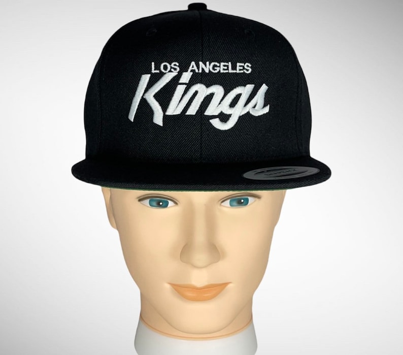 May include: Black baseball cap with a white embroidered Los Angeles Kings logo.