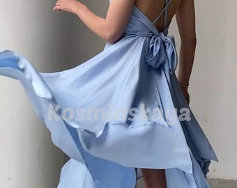 May include: A light blue satin dress with a flowing, asymmetrical hemline. The dress features a low back with crisscross straps and a large bow detail at the waist. The text "Kosminskaya" is visible on the dress.